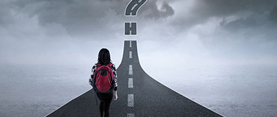 A student walking along a road that turns upward and has gaps