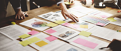 A group of people making notes with sticky notes on various documents and charts on a table