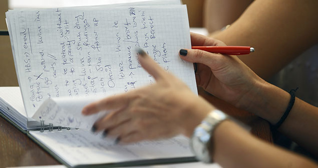 A person flipping through a notebook holding a pen