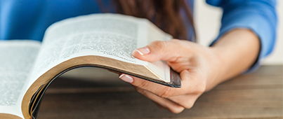 A student holding an open textbook