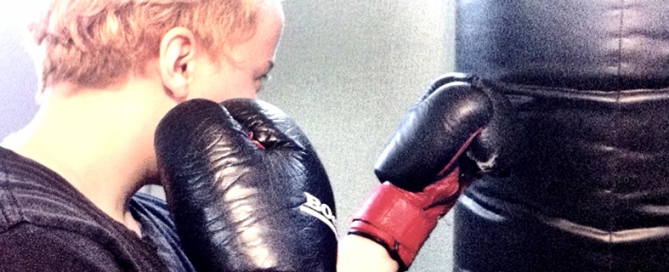 A child with boxing gloves punching a punching bag