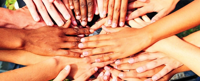 A group of children with their hands overlapping in a circle