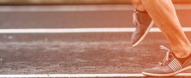 The legs and feet of a person running on a track