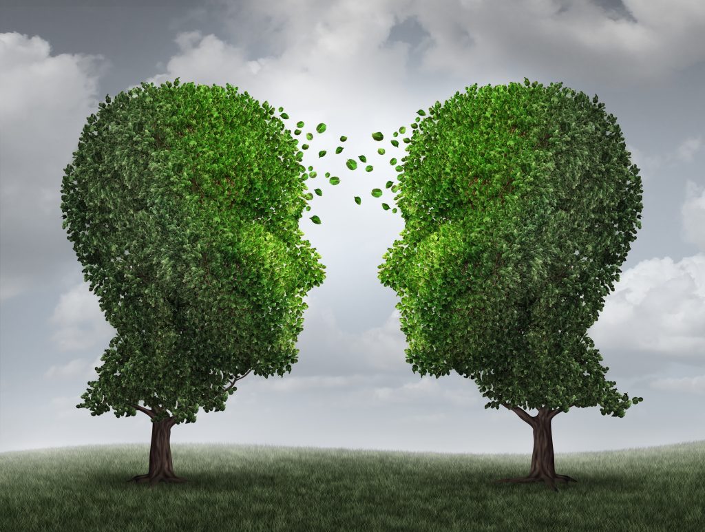 An illustration of two trees shaped like human heads with leaves flowing between