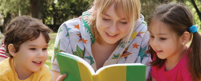 A teacher reading a book with two children